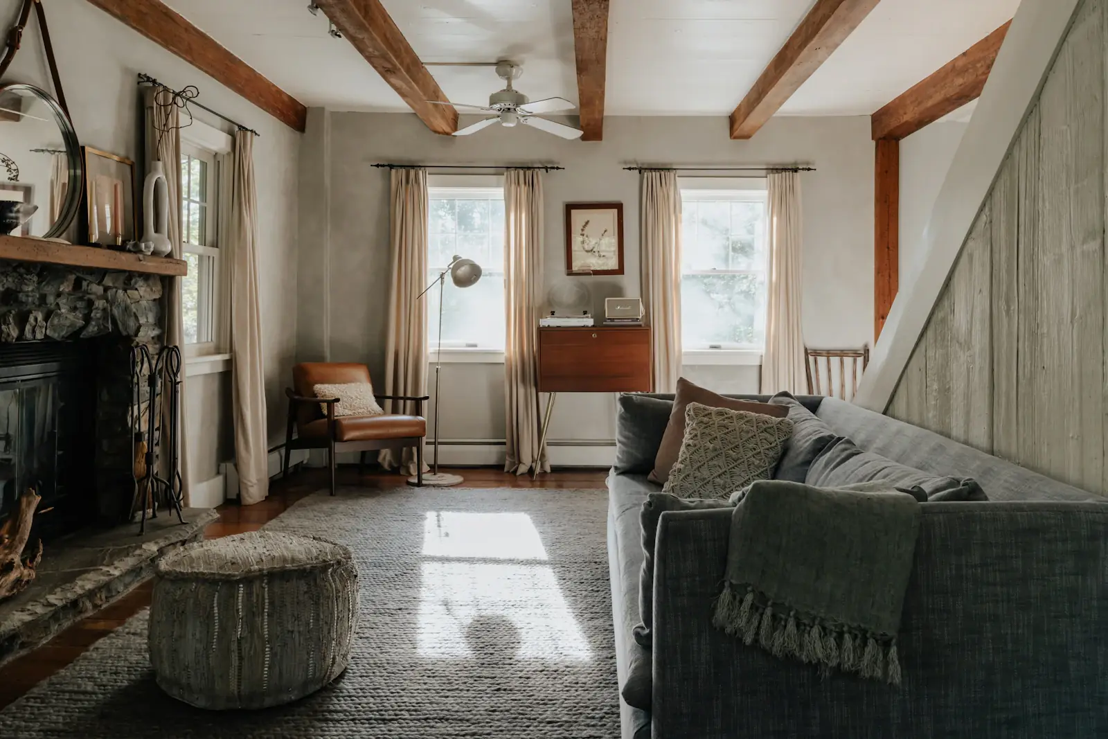 A living room with exposed beams and a stone fireplace