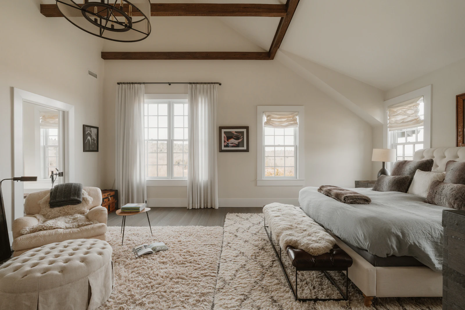 A calm main bedroom with a wool rug and upholstered bench