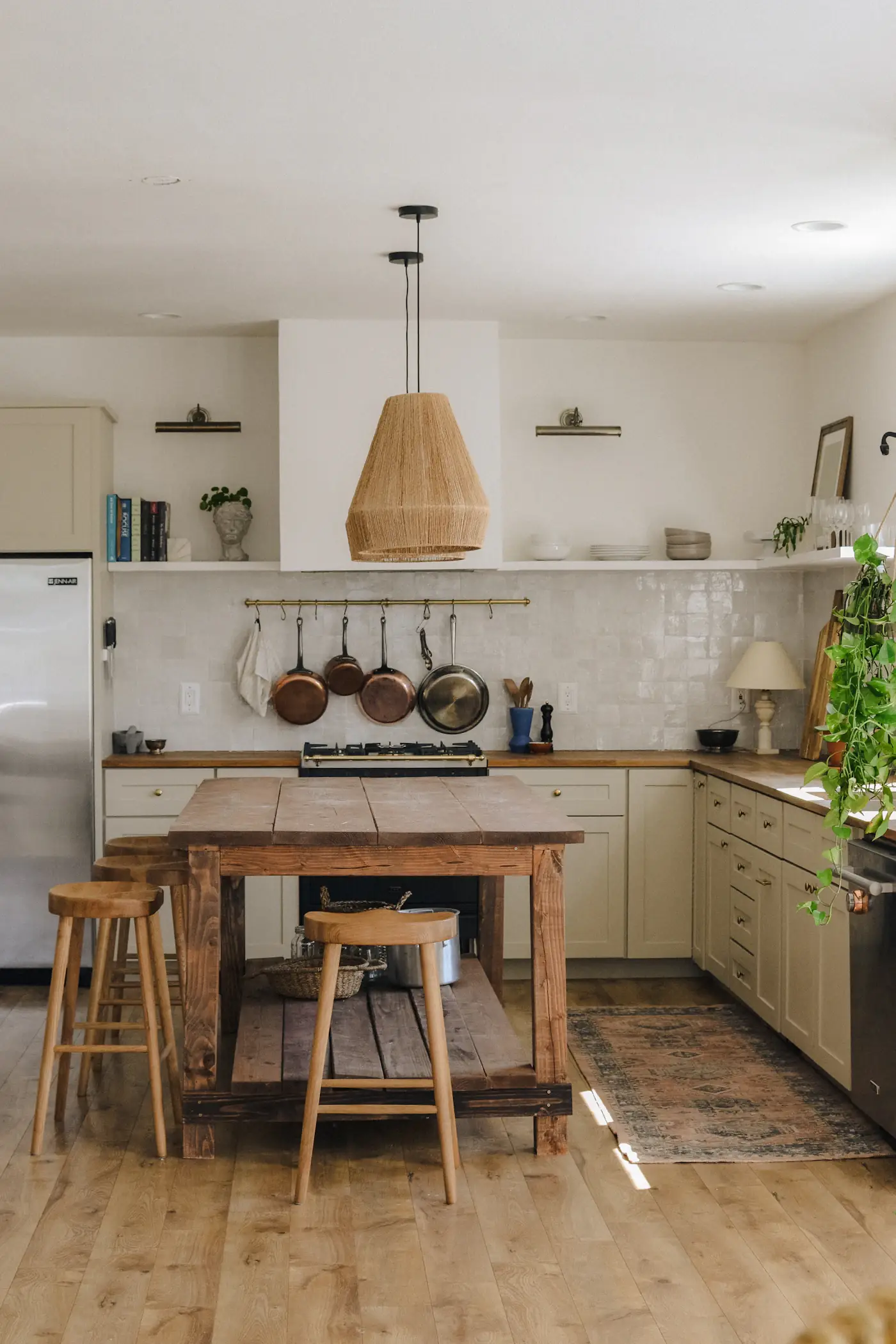 A farmhouse kitchen with an oak island and rattan pendants