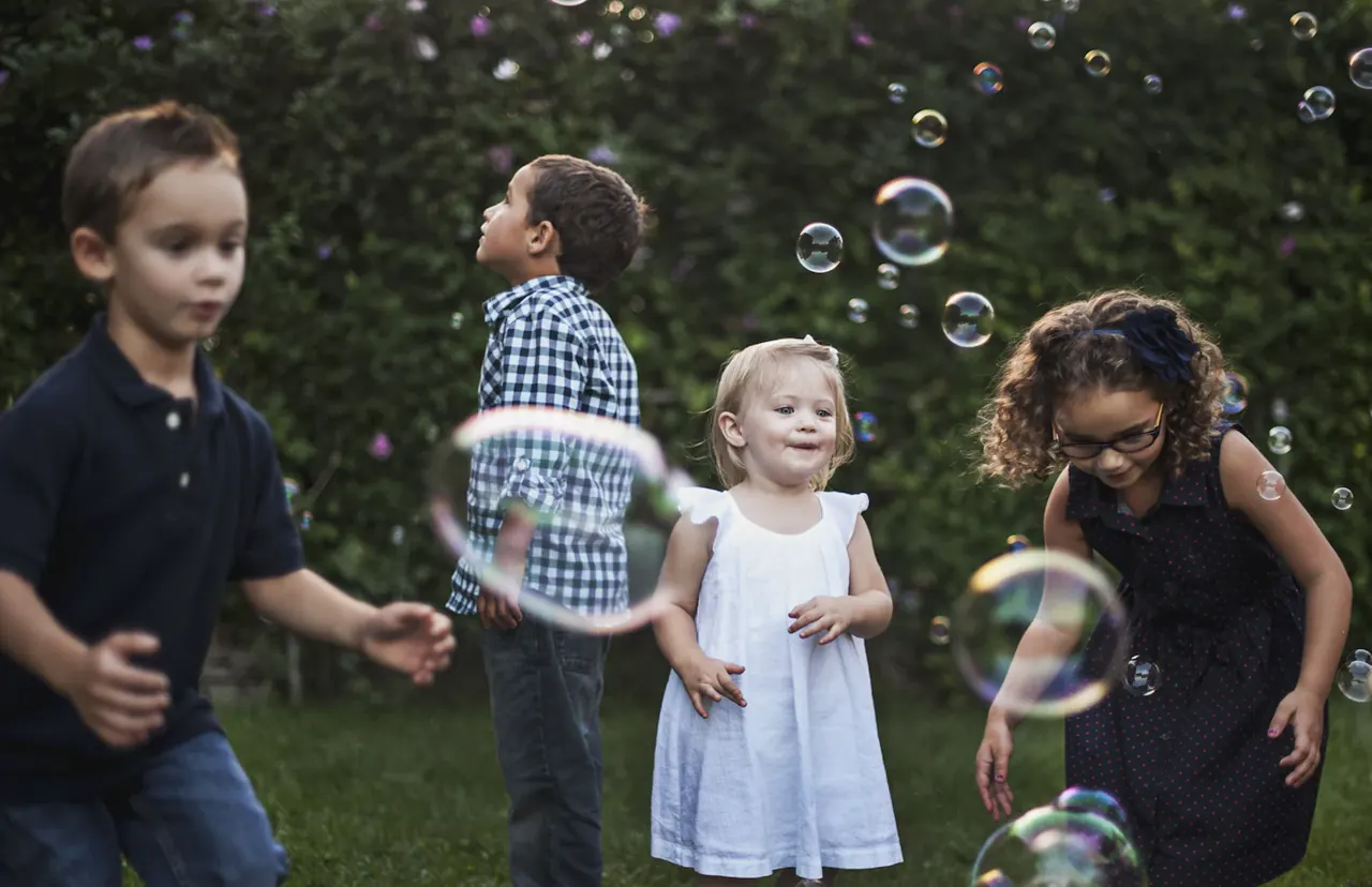 Children playing with bubbles in a green backyard