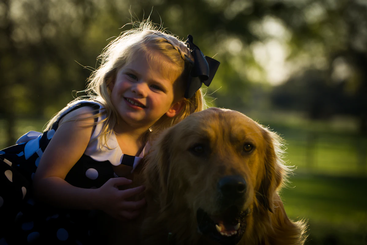 A smiling little girl hugging her golden retriever