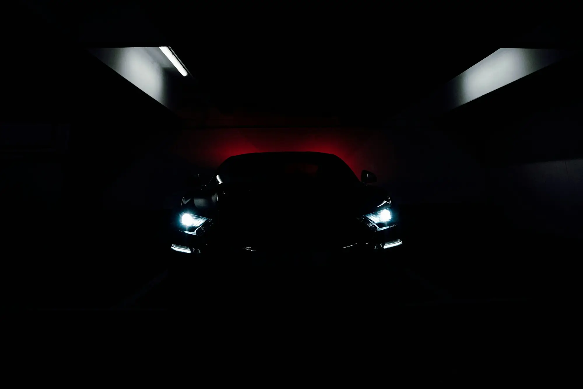 A supercar with its headlights on in a dark showroom