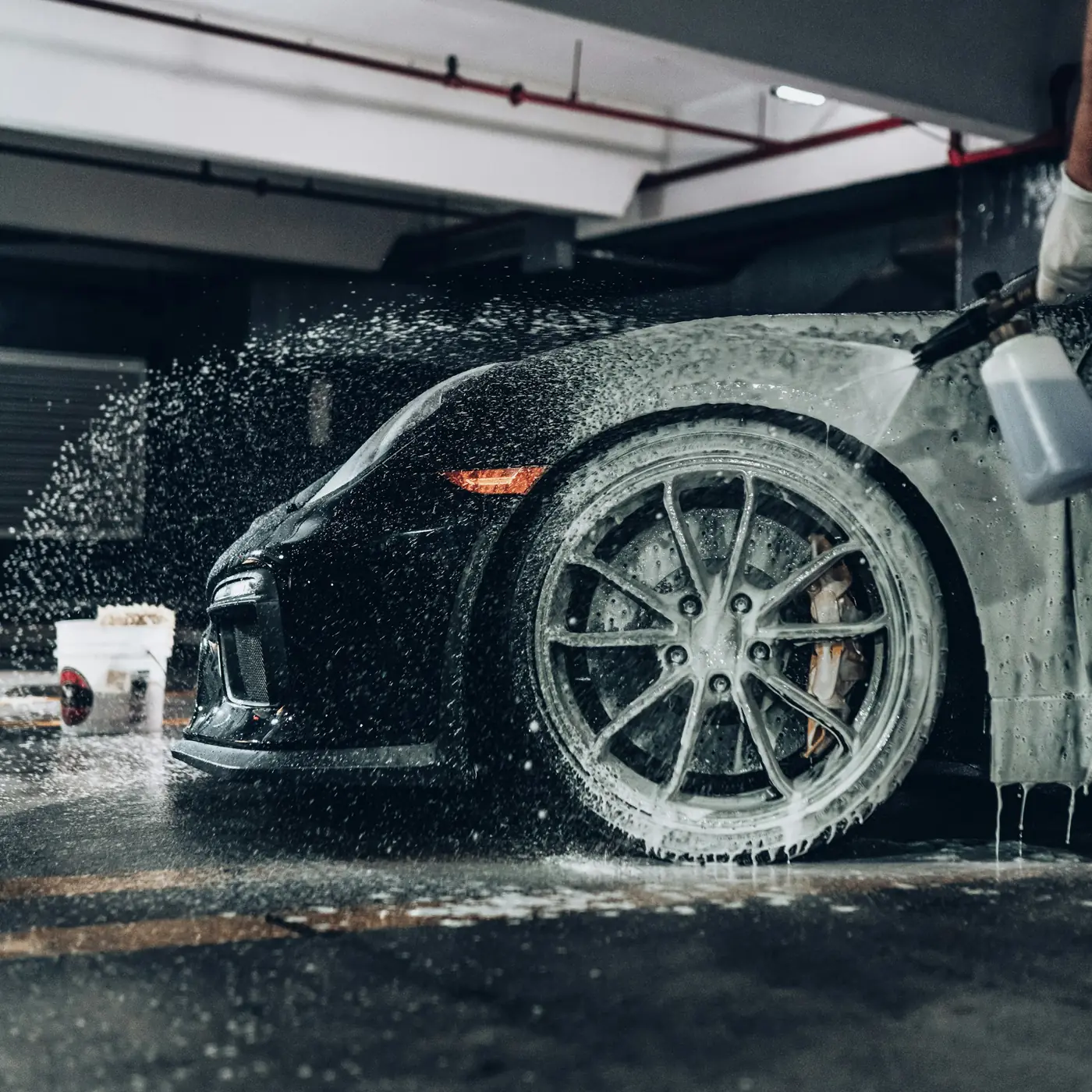 A detailer foaming a black sports car in the Kane detail bay